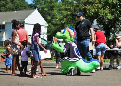 Person in dinosaur costume greets kids